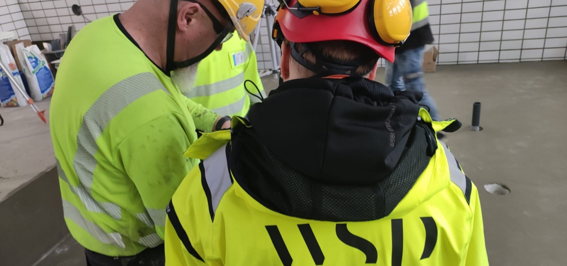 Mestarilaatoitus Oy:n Jussi Nuutinen sparrailee Mervin kanssa uima-altaan portaiden turvamerkinnöistä.