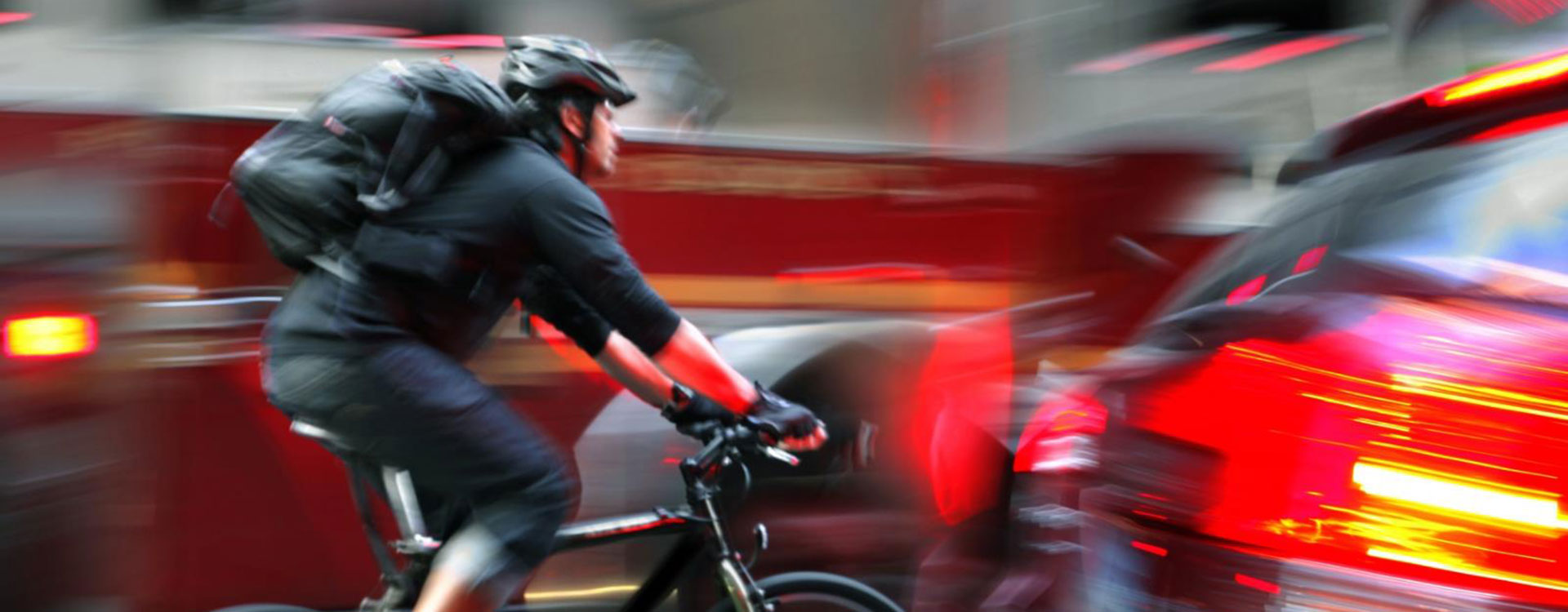Man cyklar bland bilar i stadsmiljö