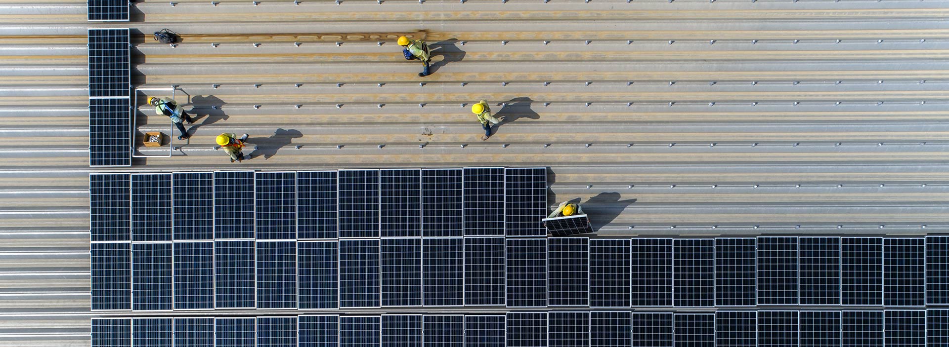 Montörer monterera ett stort antal solceller på en byggnads tak.