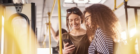 Två personer på en buss som kollar ner i telefonen.