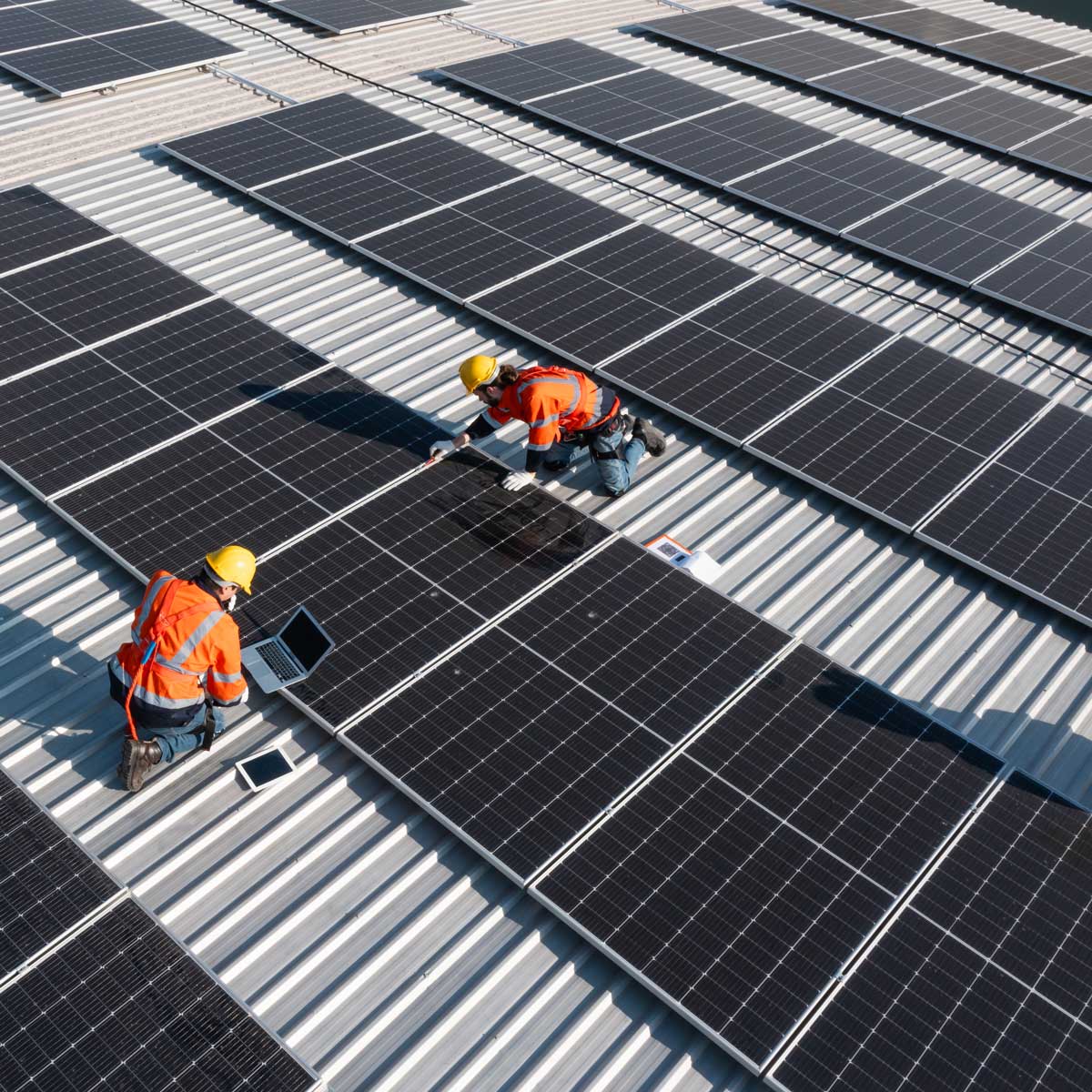 Två personer som jobbar med solceller på en byggnad.