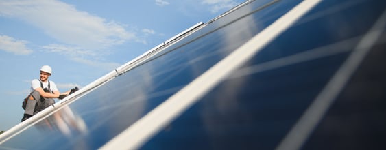 Person som jobbar med solceller på en byggnad.