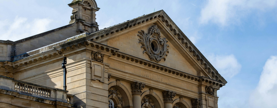 A picture of the face of Cheltenham Town Hall in Gloucestershire in the UK. The town hall is designed in classical style with three bays and three Corinthian columns on both the first and second storey, the frontage has a large decorative pediment at the top