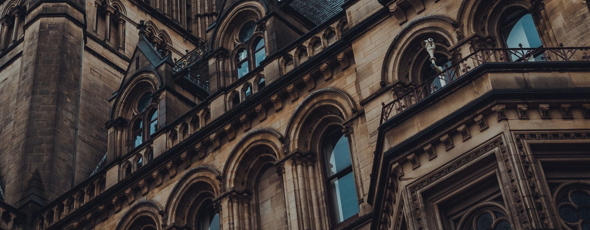 The image features a cross section of Manchester City Hall which is a grey building that is gothic by design