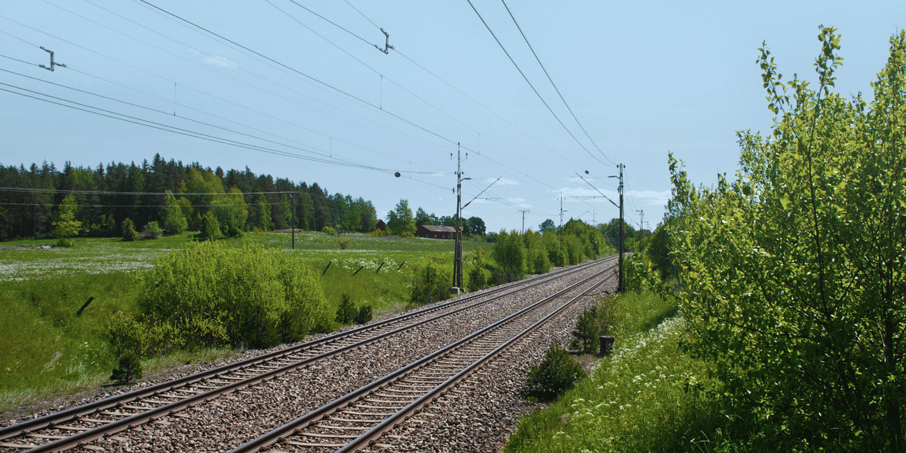 Järnvägsspår med grönska runtom.