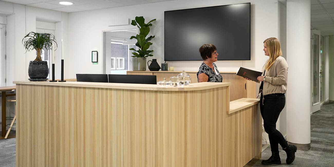 Medarbetare interagerar med varandra i reception som uppfyller WSPs krav på hållbarhet och attraktivt kontorsmiljö.