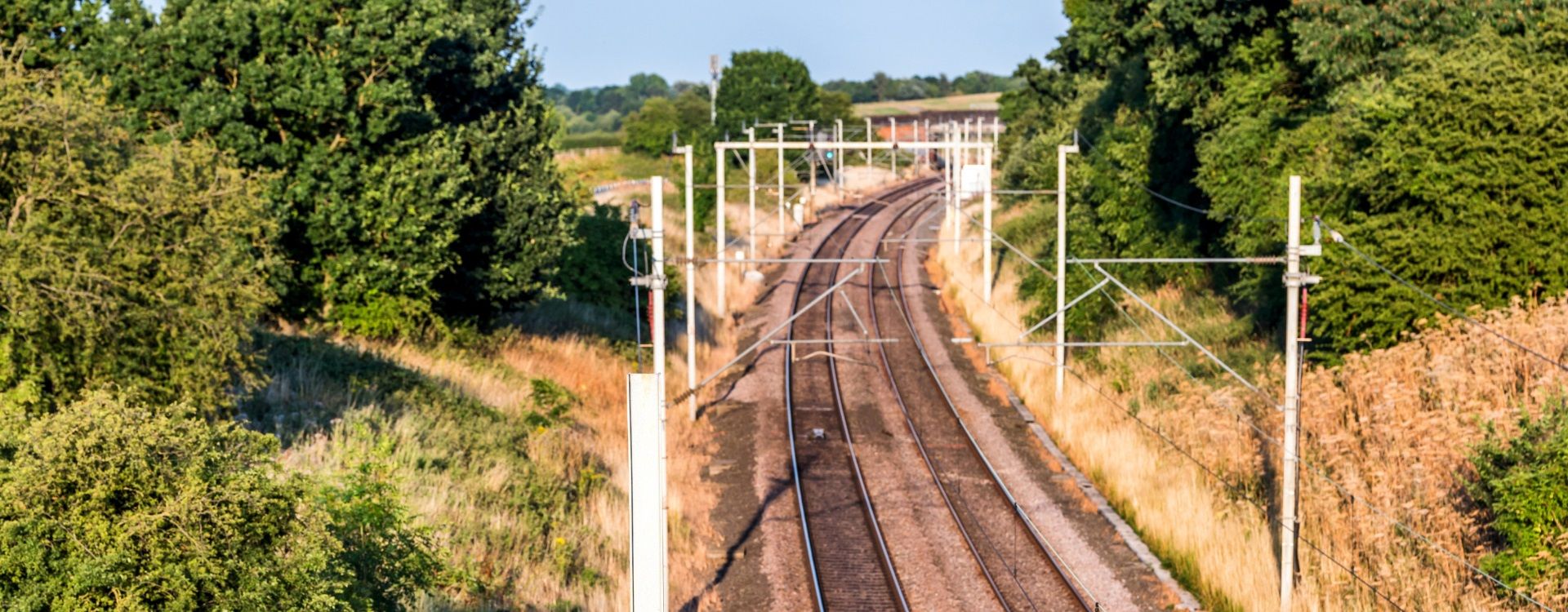 Railway stretching through grassland and trees