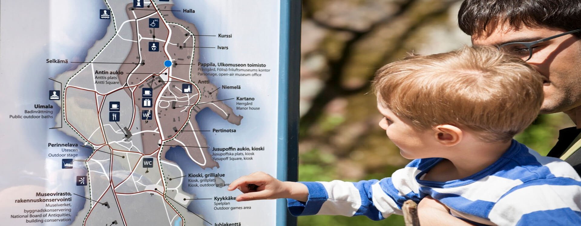 Mies ja lapsi tutkimassa Seurasaaren opasteita