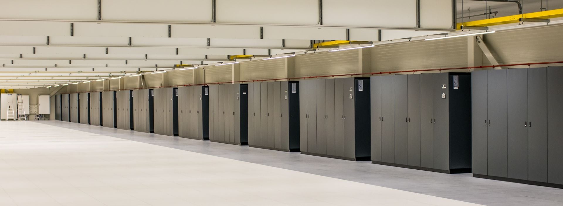 Data center corridor with rows of gray server cabinets in a clean, modern facility.