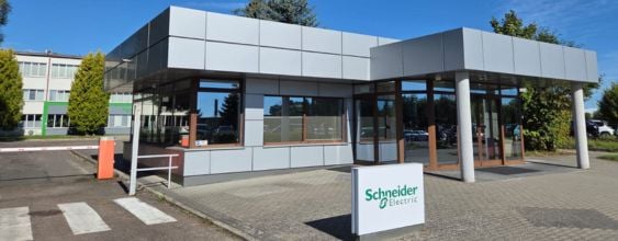 Modern office building with glass entrance, grey facade panels, and Schneider Electric signage.