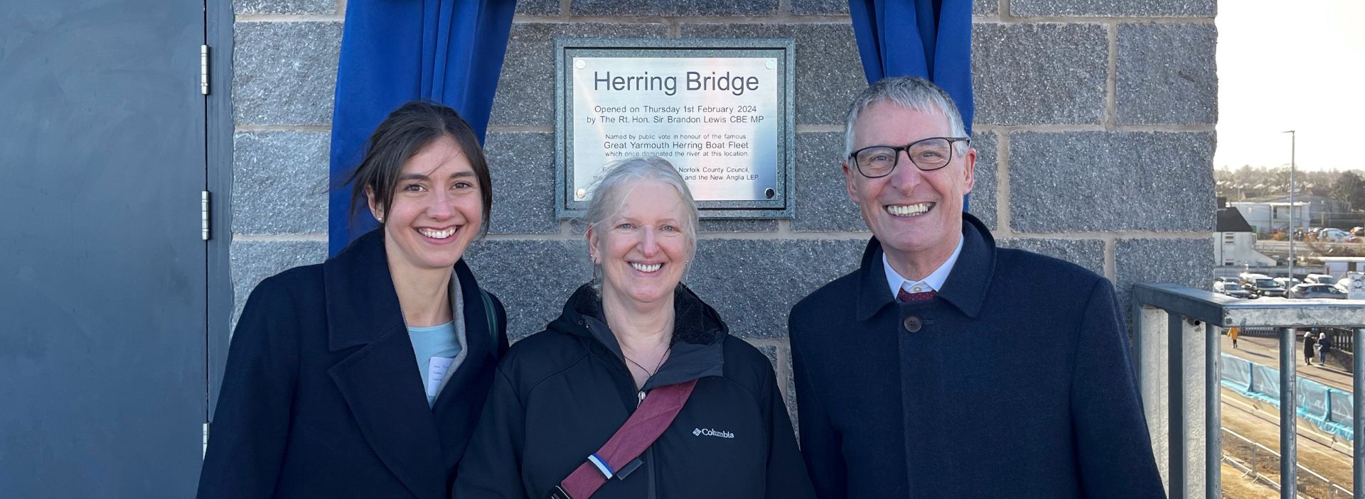 A picture of WSP’s project team Jennifer Warhurst, Charles Ferrar and Joanna Lyon in front of a plaque marking the opening of the Herring Bridge in Great Yarmouth