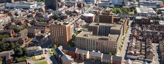 A computer generated illustration showing the new Gresham masterplan in situ within Middlesbrough town centre. The development is a mid-rise development and is surrounded by a mixture of other residential developments, including back to back terraces to the right. The town centre is in the background.