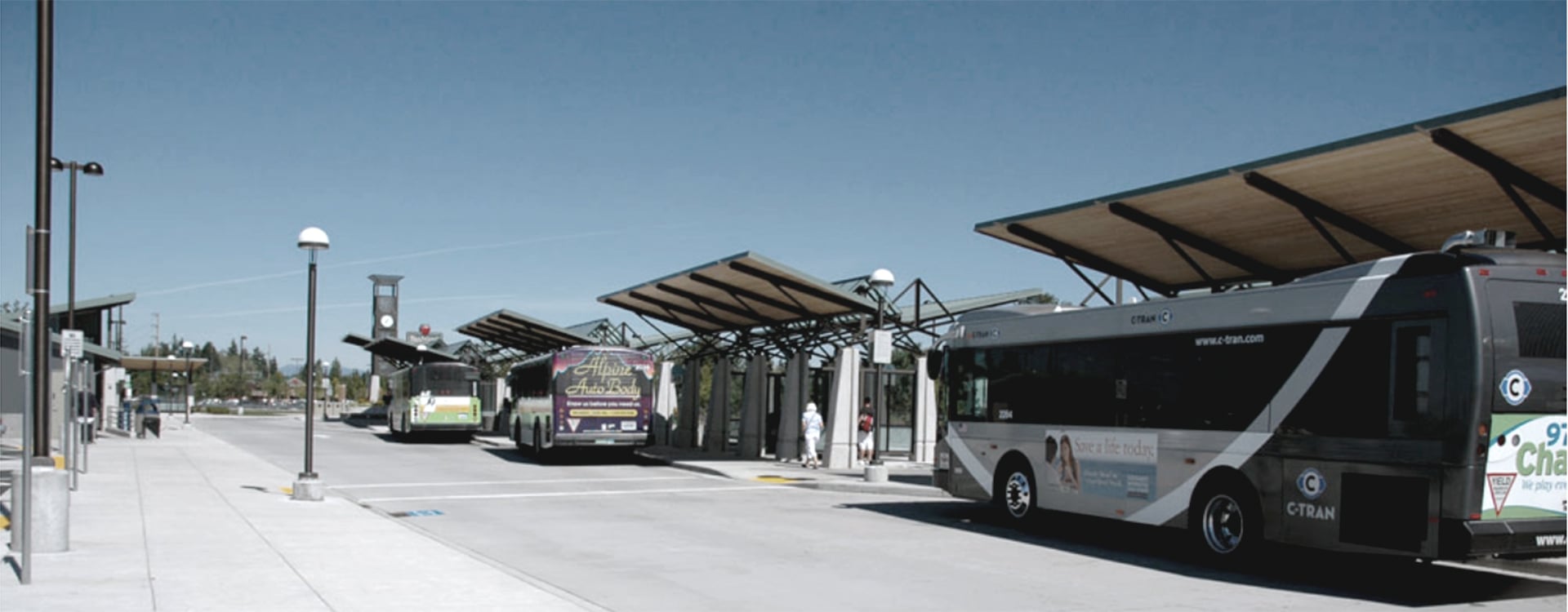 Outdoor view of bus transit center where several buses are parked under curbside canopies