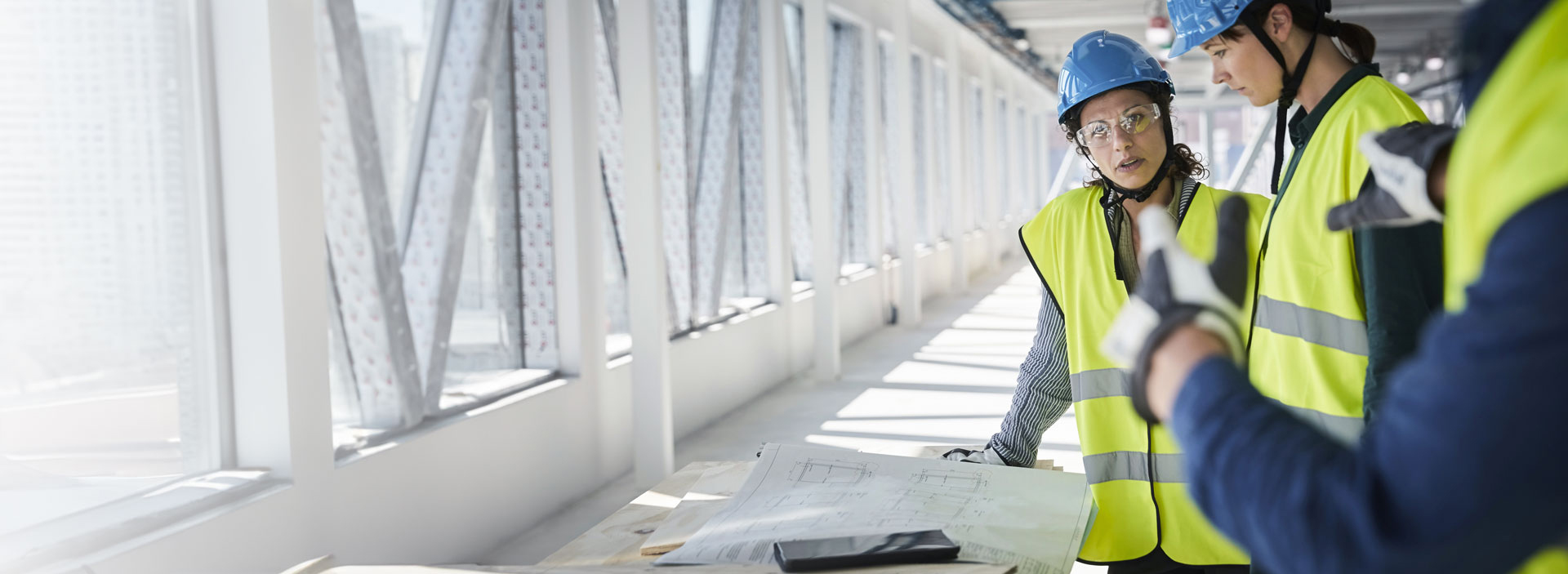 En byggledning i varselkläder som står i bygget och ser över projektet.